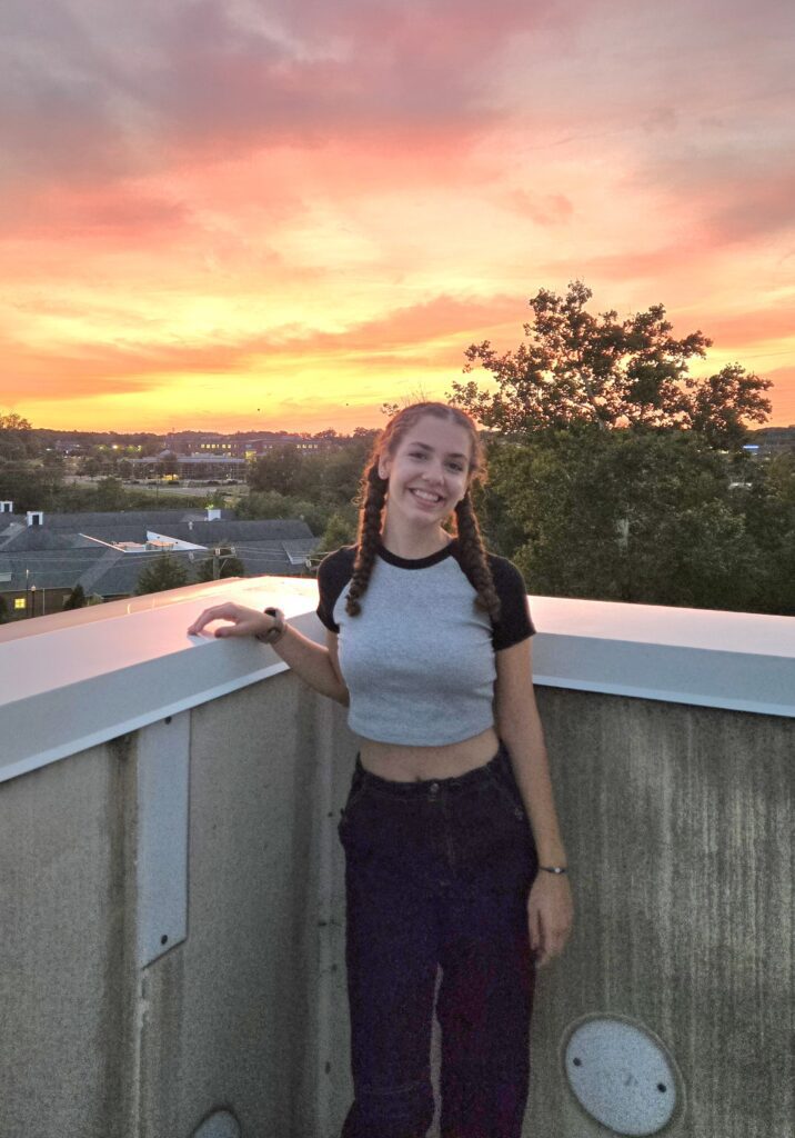 Female smiling standing in front of a sunset